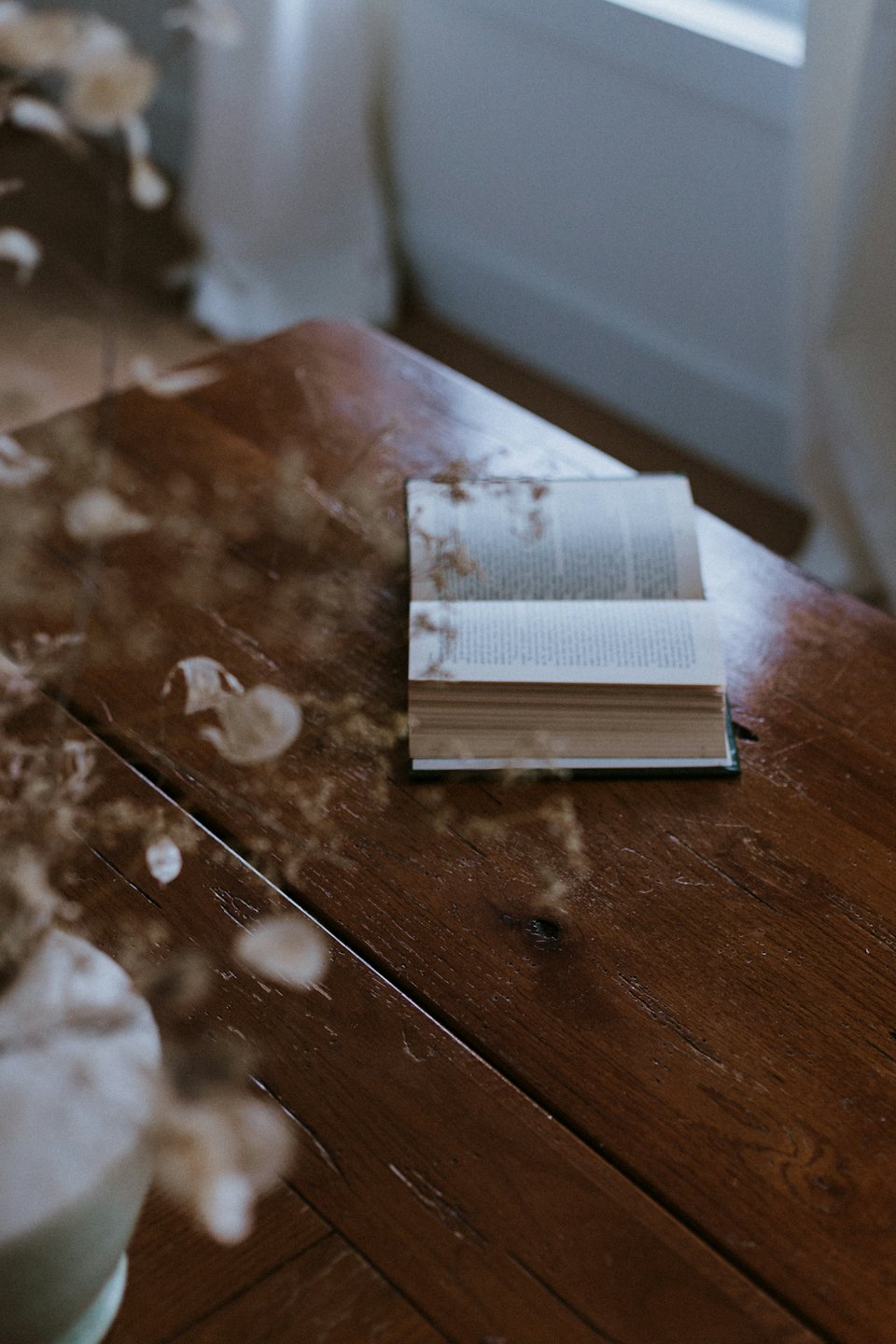 Un libro aperto giace su un tavolo di legno rustico.