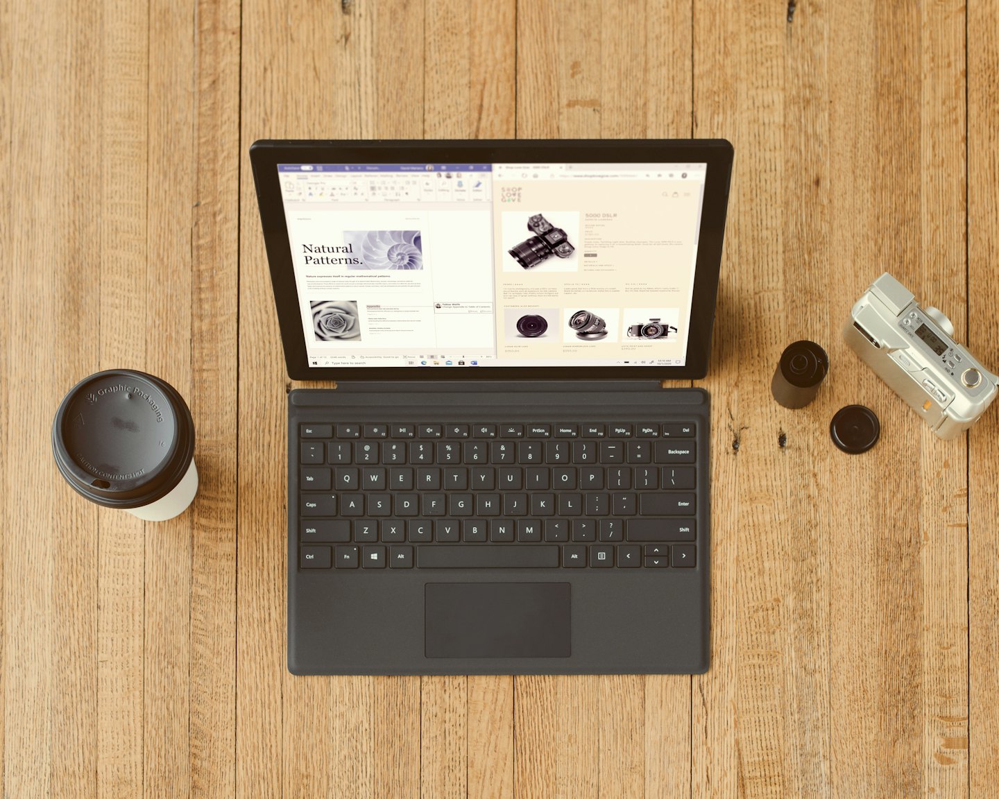 Laptop, tazza di caffè e macchina fotografica disposti su una scrivania di legno.
